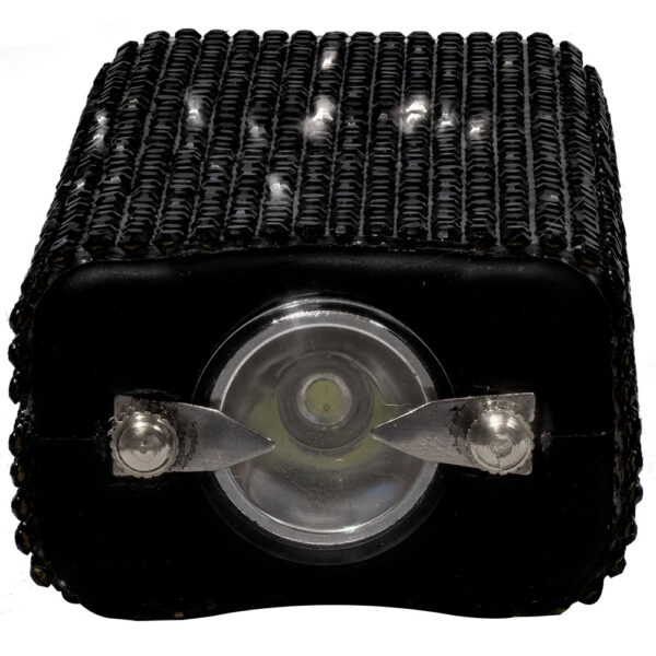 The image features a close-up view of a black mechanical component, possibly a heat sink or electronic device, with a cylindrical protrusion at its center. The surface is textured with multiple rows of small, uniform bumps or fins that may aid in heat dissipation. The central cylindrical part appears to be metallic, with a transparent lens covering it, possibly indicating