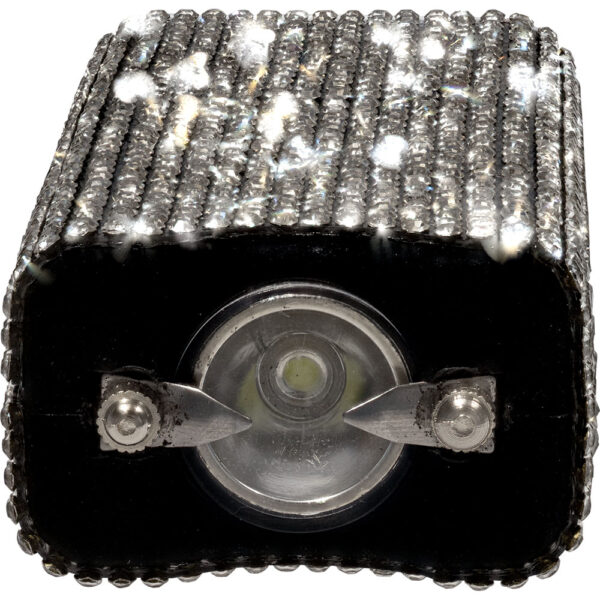 This image showcases a luxurious pencil sharpener adorned with intricate, sparkling crystals. The sharpener features two metal blades, visible in the center, designed for effective sharpening. The body is covered in a grid-like pattern of rhinestones that shimmer and reflect light, giving it an elegant and glamorous appearance. The crystals add a unique and decorative touch, making it