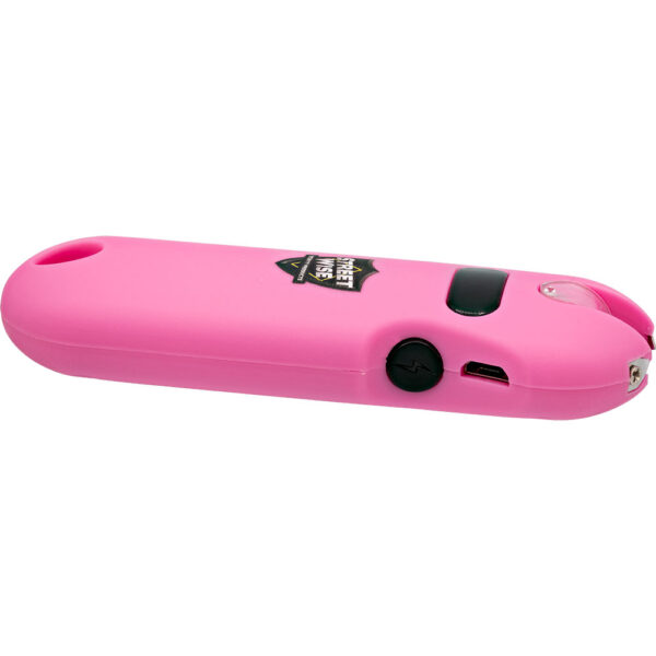 The image shows a pink electronic safety device designed for personal protection. The device has a sleek, elongated shape with a curved, ergonomic design. It features a black button with a lightning bolt symbol, indicating its stun gun functionality. Near this button, a micro USB charging port is visible, suggesting it is rechargeable. There is a clear protective cover over the