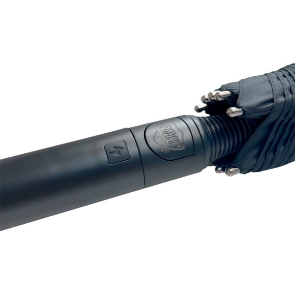 The image showcases a close-up of a black, cylindrical baton, part of a tactical self-defense tool. It features a logo or emblem with the words Street Angel prominently displayed. The baton has a sleek, matte finish with a visible power symbol near the top, indicating a potential electrical or high-tech feature. Next to the handle is a folded