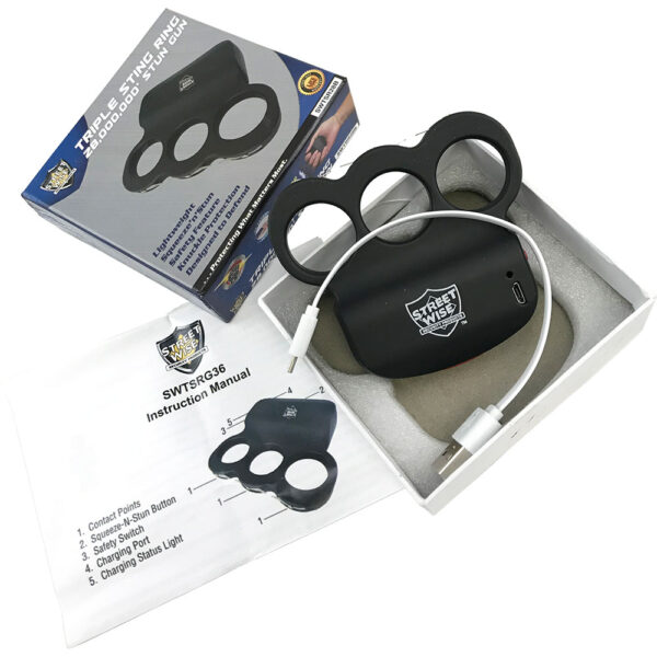 The image features the packaging and contents of the Streetwise Triple Sting Ring stun gun. The product includes a black stun gun with a brass knuckle design capable of delivering 28,000,000 volts. The device is nestled in a white foam box insert with a USB charging cable included. The product box displays the Streetwise logo and highlights features such